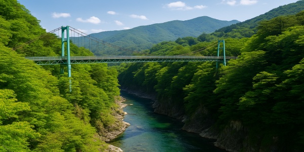 新緑の塩原渓谷を渡る吊り橋と下を流れる清流、背景には連なる山々