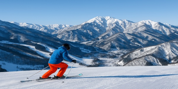 苗場スキー場で滑走するスキーヤーと雪山のパノラマ