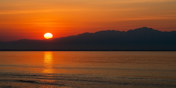 富山湾越しに沈む夕日と立山連峰の絶景